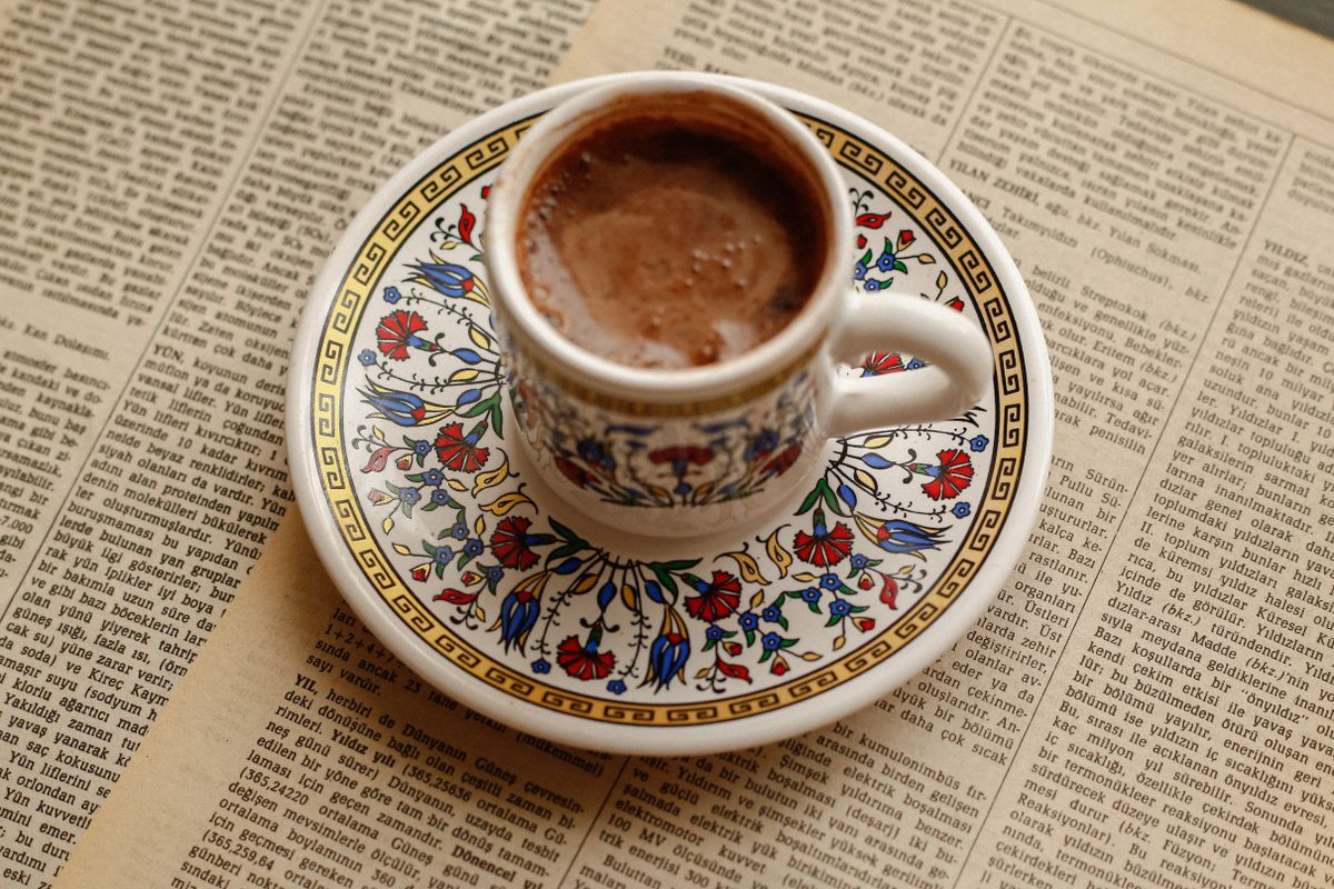 Nostaljik bir gazete üzerinde, süslü porselen fincanda köpüklü Türk kahvesi